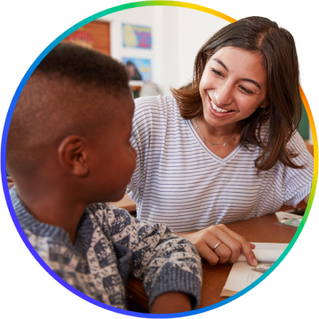 A teacher happily assisting a student with work.